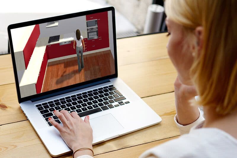 Frau vergleicht Küchenangebote zu Hause am Laptop mit 3D-Planung