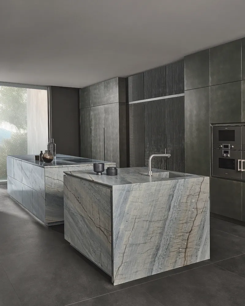Minimalistische Küche mit Kochinsel in Naturstein hell, grau-beige geädert mit Arbeitsplatte aus Naturstein geädert 30 mm von Eggersmann