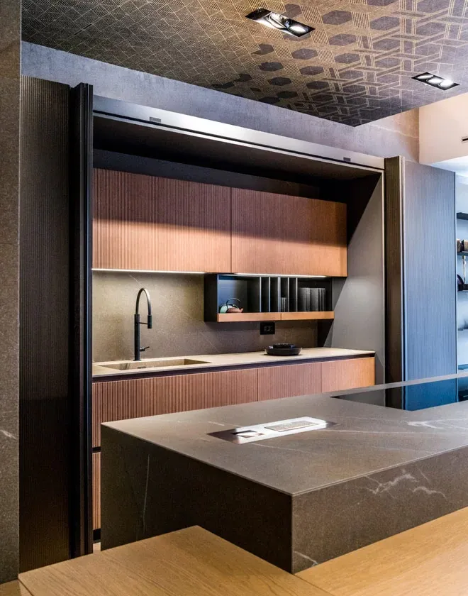 Moderne Küche mit Kochinsel in Kupfer gebürstet mit Rillenstruktur, Arbeitsplatte aus Keramik Betonoptik grau von Pedini
