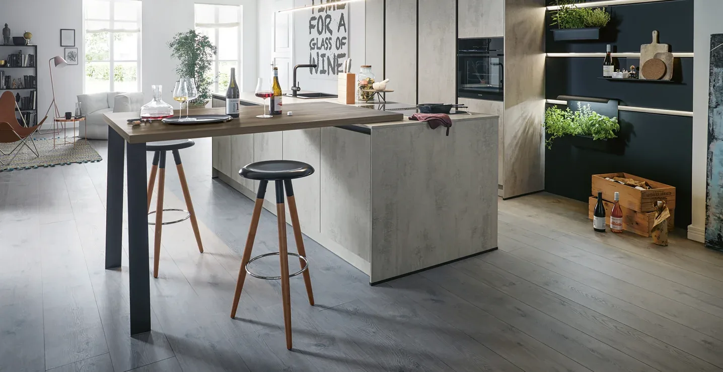 Schüller Küche in Beton-Optik mit Bartheke und grüner Kräuterwand