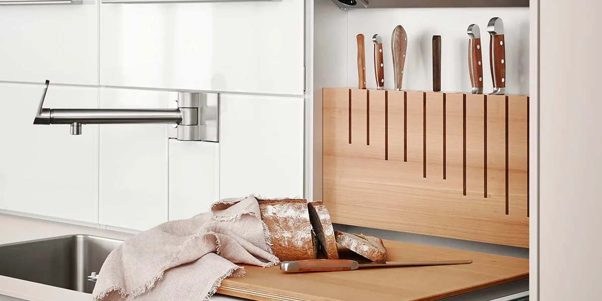 bulthaup b3 Funktionswand mit integriertem Messerblock aus Holz, Küchenmessern und einem Schneidebrett mit frischem Brot