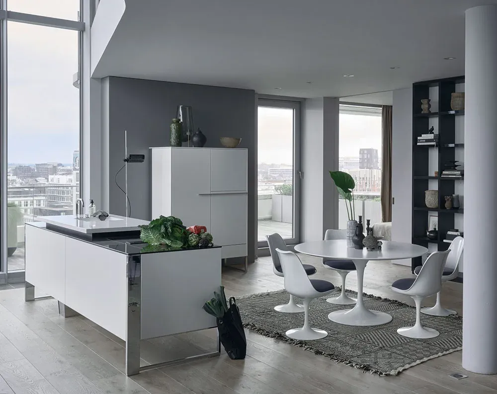 Grifflose Inselküche in Weiß mit filigranen seitlichen Metallrahmen, schwebende Optik im Penthouse