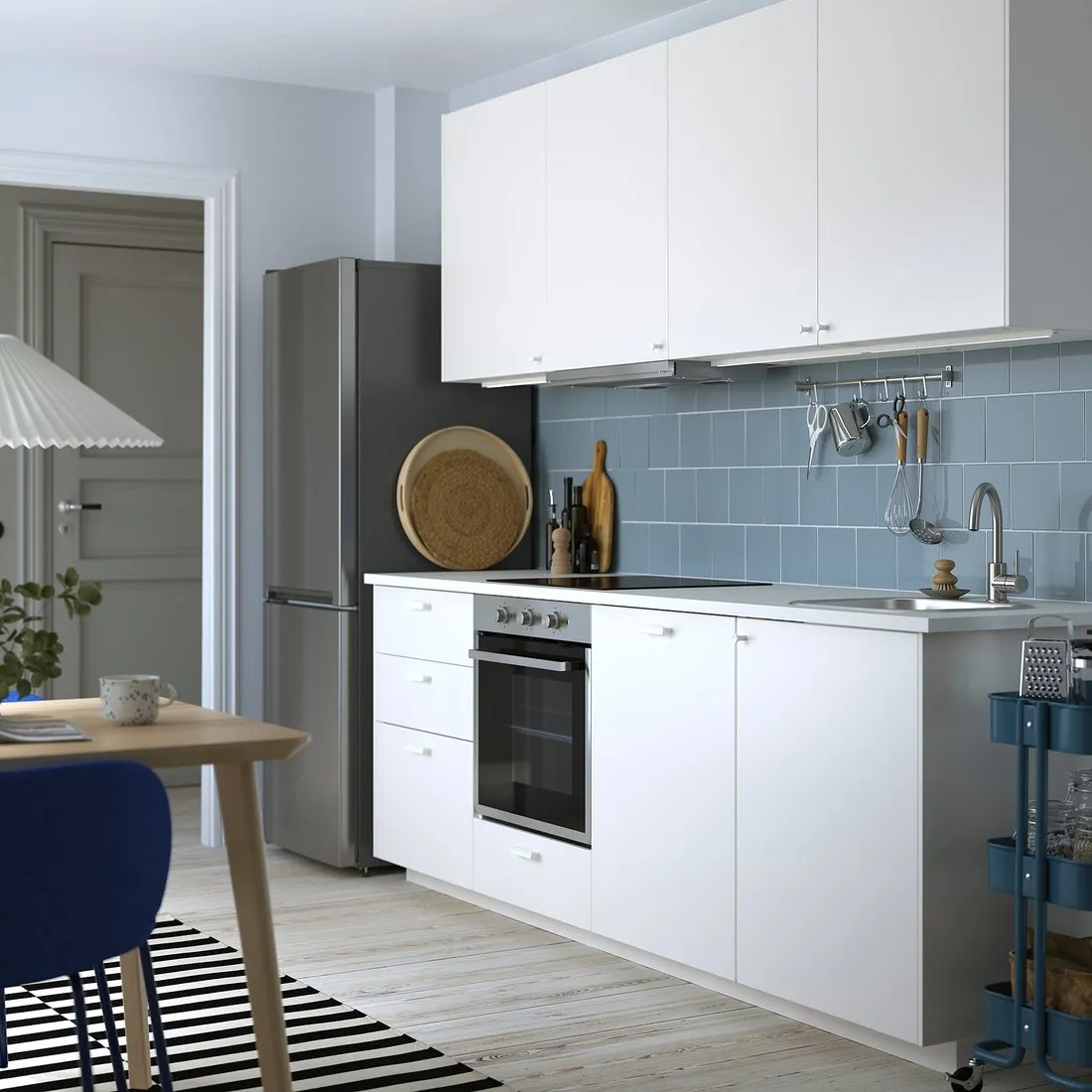 Weiße IKEA METOD Küchenzeile mit blauem Fliesenspiegel und freistehendem Kühlschrank